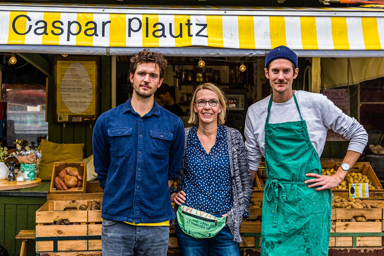 Dominik Klier und Theo Lindinger zusammen mit Reporterin Angela Berg vor den Speisekartoffeln von Caspar Plautz. Zur Zeit ist die Auswahl auf 12 Sorten begrenzt. Zum Herbst hin weitet sich das Angebot auf bis zu 25 Sorten aus / © Foto: Georg Berg