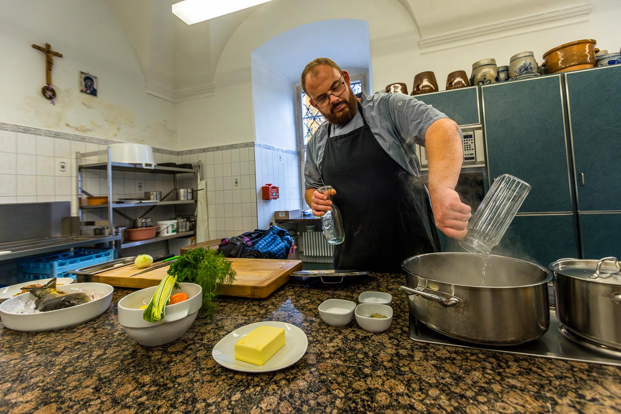 Koch Benjamin Standfest bereitet den Sud aus Essig und Wasser sowie Gemüse und Karpfenkopf für den Klassiker Karpfen blau vor / © Foto: Georg Berg