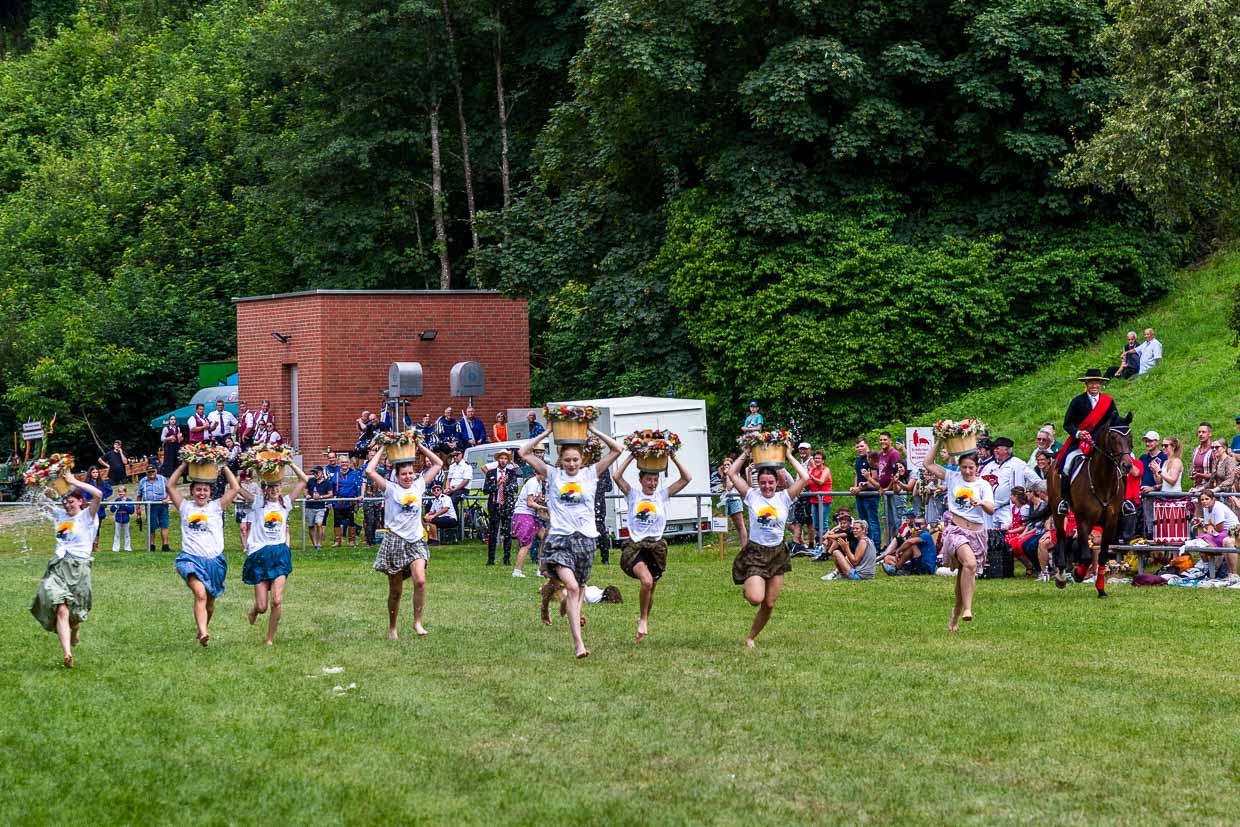 Schülerinnen beim Wasserkübellauf. Bei dem Lauf treten junge Frauen der neunten und zehnten Klasse des Bildungszentrums Wildberg mit Wasserkübeln auf dem Kopf in einem Wettlauf gegeneinander an. Dieser Lauf ist ein fester Bestandteil des Schäferlaufs und symbolisiert die früheren Aufgaben der Schäfermädchen und -frauen, die Wasser für Mensch und Tier herantragen mussten. Er erinnert an die harte körperliche Arbeit und das Geschick, das im Alltag der Schäferei notwendig war / © Foto: Georg Berg