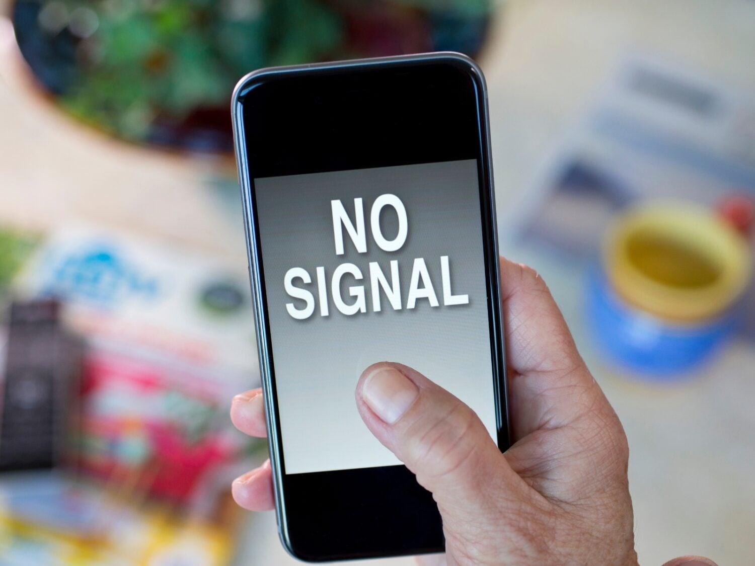 hand holding cell phone that displays NO SIGNAL