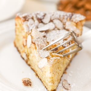 taking a bite of a slice of almond croissant cake.