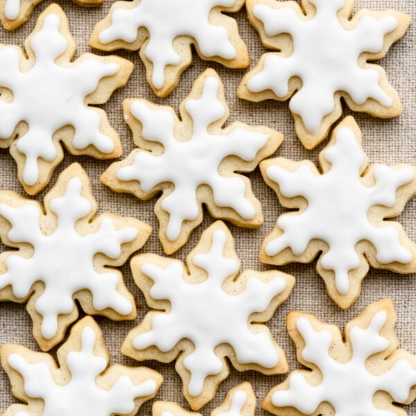 Overhead of snowflake shaped cookies with white icing on a cloth.