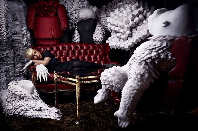 a woman lying on a couch with white paper sculptures