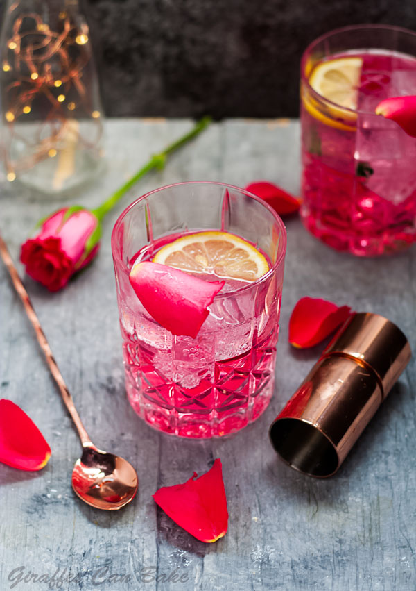 This Rose Vodka Tonic is a delicious upgrade on the classic Vodka Tonic mixed drink! With Rose Liqueur, it’s delicately floral and perfect for bridal and baby showers, brunch, and Mother’s Day! Rose Vodka Tonic Mixed Drink Cocktail - above view of cocktail in rocks glass with rose, jigger and stirrer surrounding