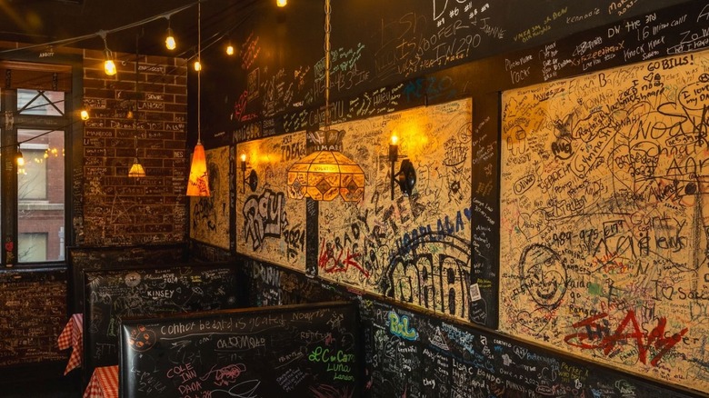 Booths and walls of inside a restaurant covered in graffiti.