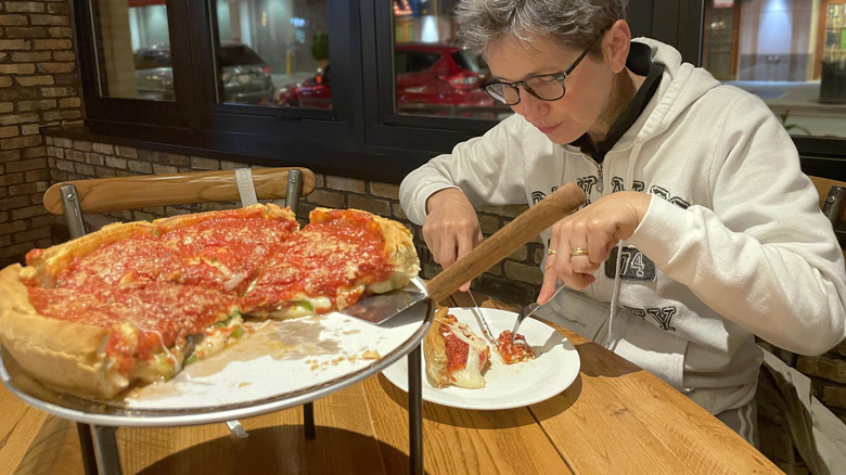Woman cutting a Chicago-style deep dish pizza