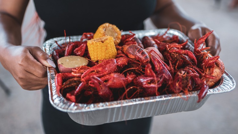 Woman holding crawfish boil in an aluminum pan