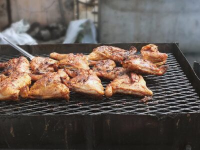 Image of meat barbecuing on black oil drums in the Caribbean.