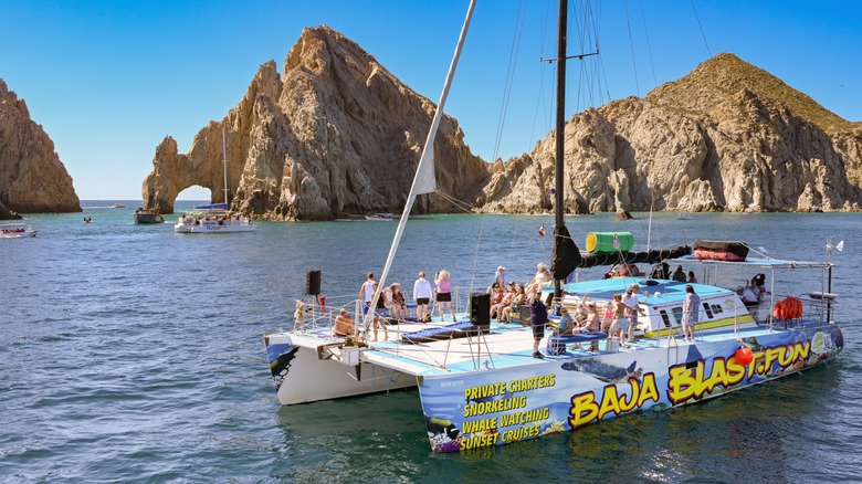 People on the deck of a catamaran in the bay of Cabo San Lucas for a party cruise.