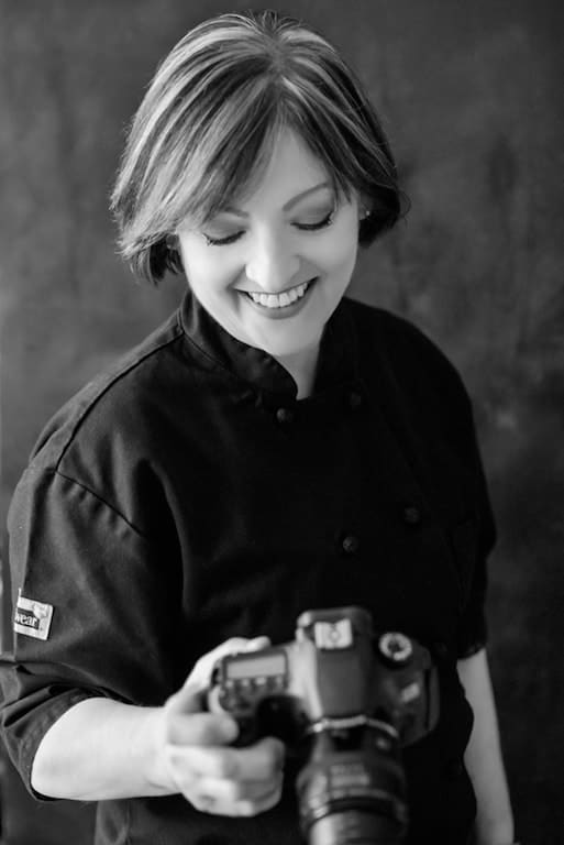 Carol Borchardt in black chef's jacket holding a camera.