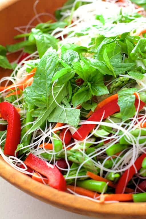 Close-up photo of salad in wooden bowl with chopped mint on the top.