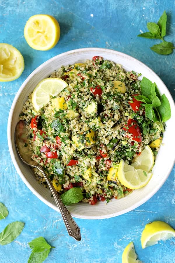 Photo of Quinoa Tabbouleh with Grilled Vegetables in white serving bowl on blue background.