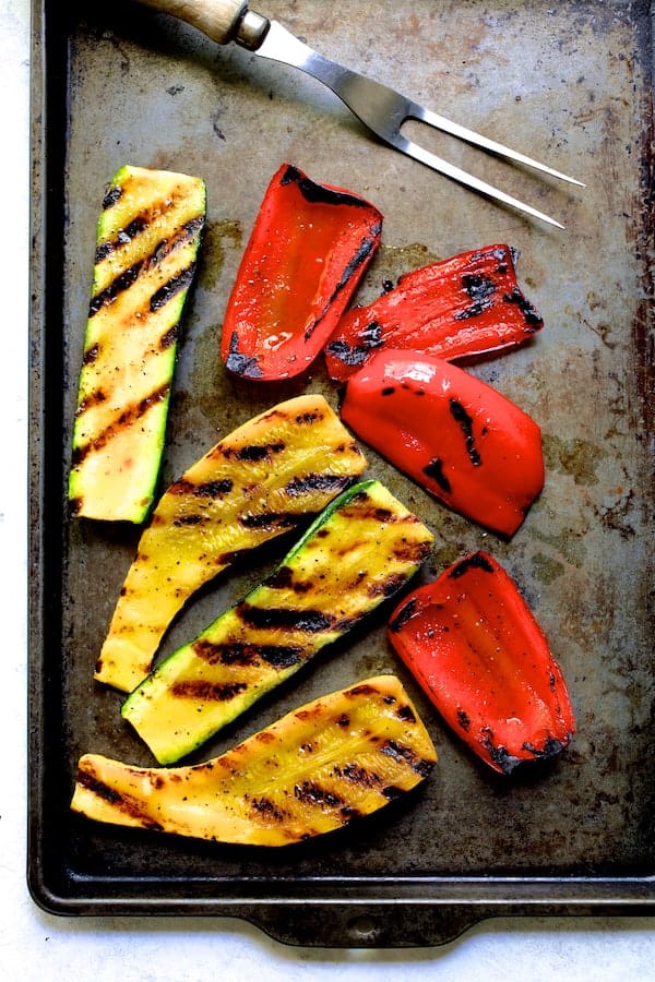 Photo of grilled yellow squash and red bell pepper on baking sheet.