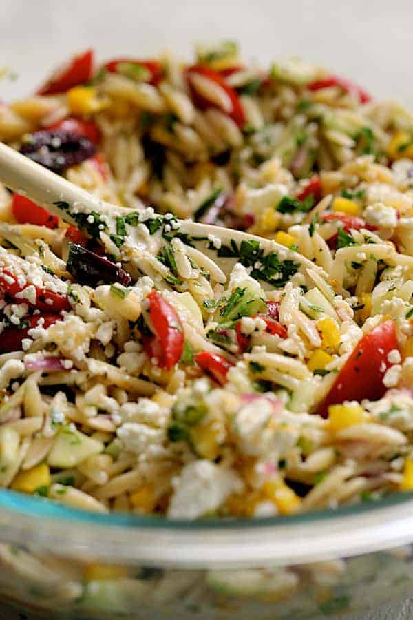 Photo of salad being mixed together with feta cheese added.