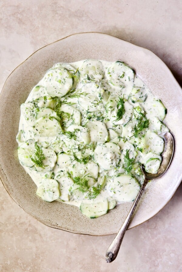 Creamy Cucumber Salad with Yogurt in serving bowl with antique serving spoon.