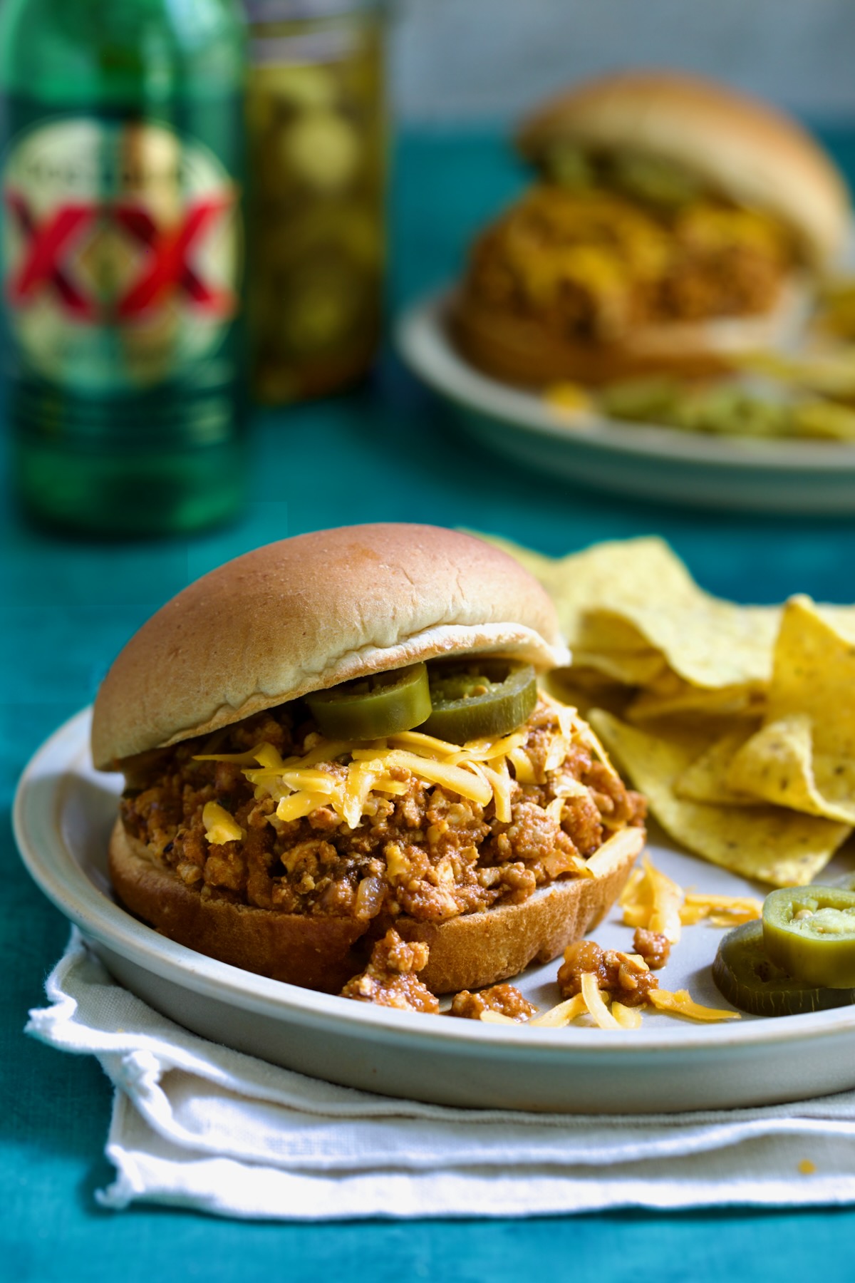 Chicken Sloppy Joes on plate with tortilla chips and jalapeno slices.