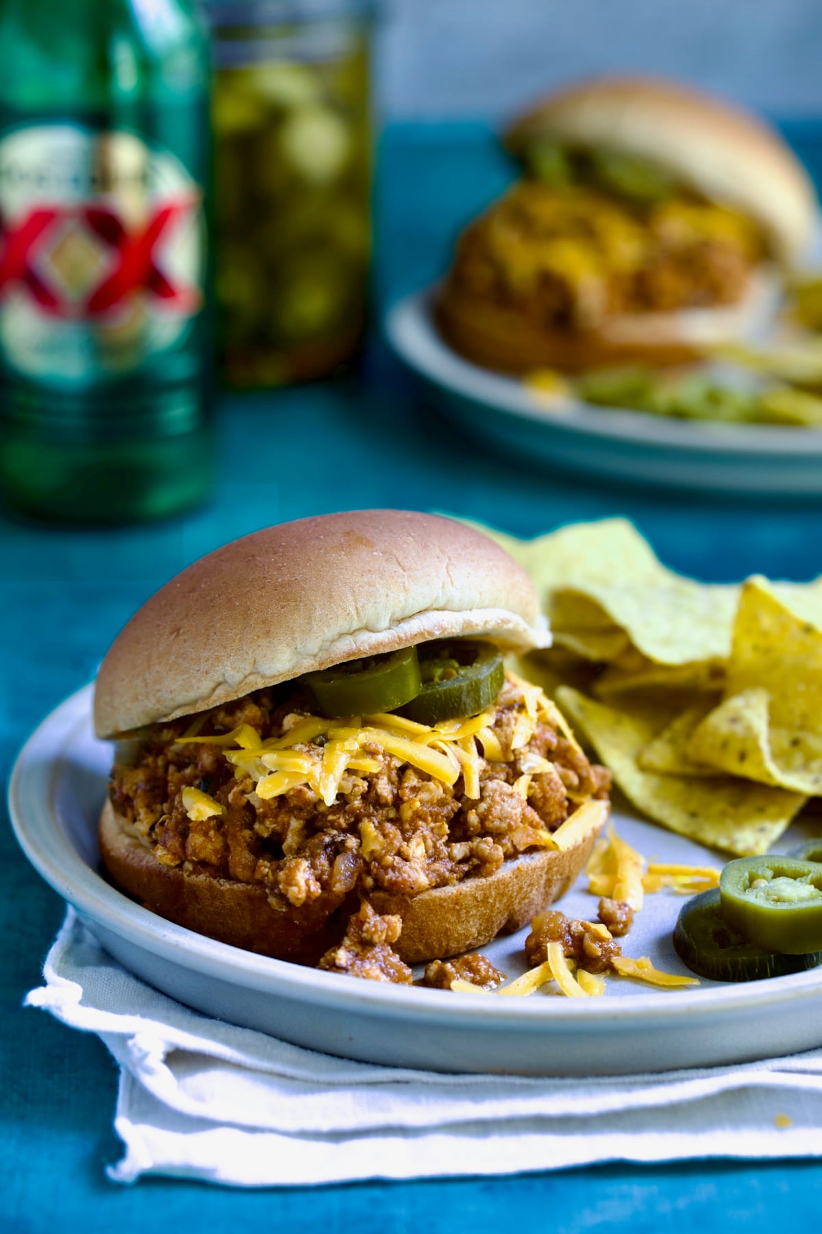 Chicken Sloppy Joes on plate with tortilla chips and jalapeno slices.