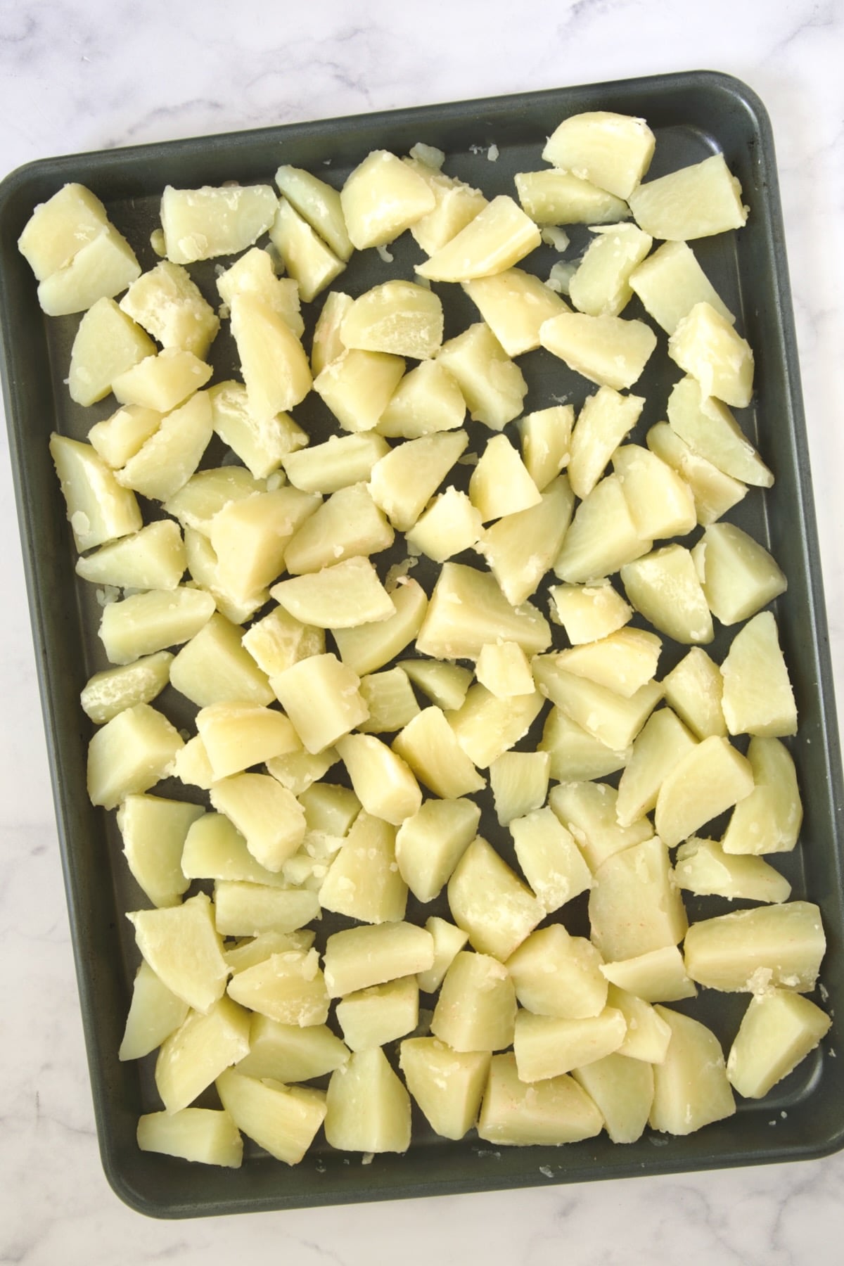 Cooked potatoes on rimmed sheet pan.