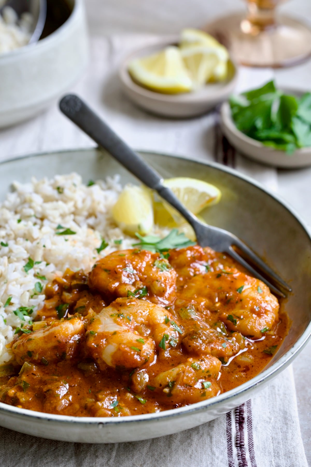 Best Shrimp Creole in beige serving bowl with brown rice and lemon wedges with fork.