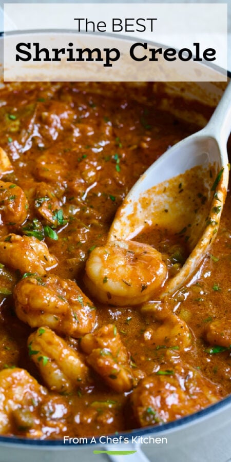 Pinterest graphic for Shrimp Creole showing it in a white cast iron skillet with white spoon scooping up one of the shrimp.