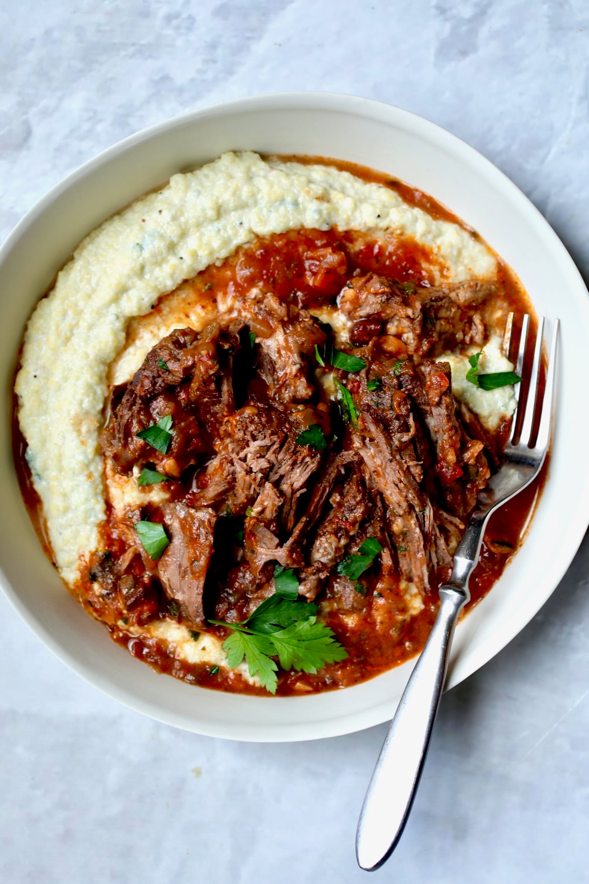 One serving of Italian Pot Roast (Stracotto) in white dinner bowl with fork.