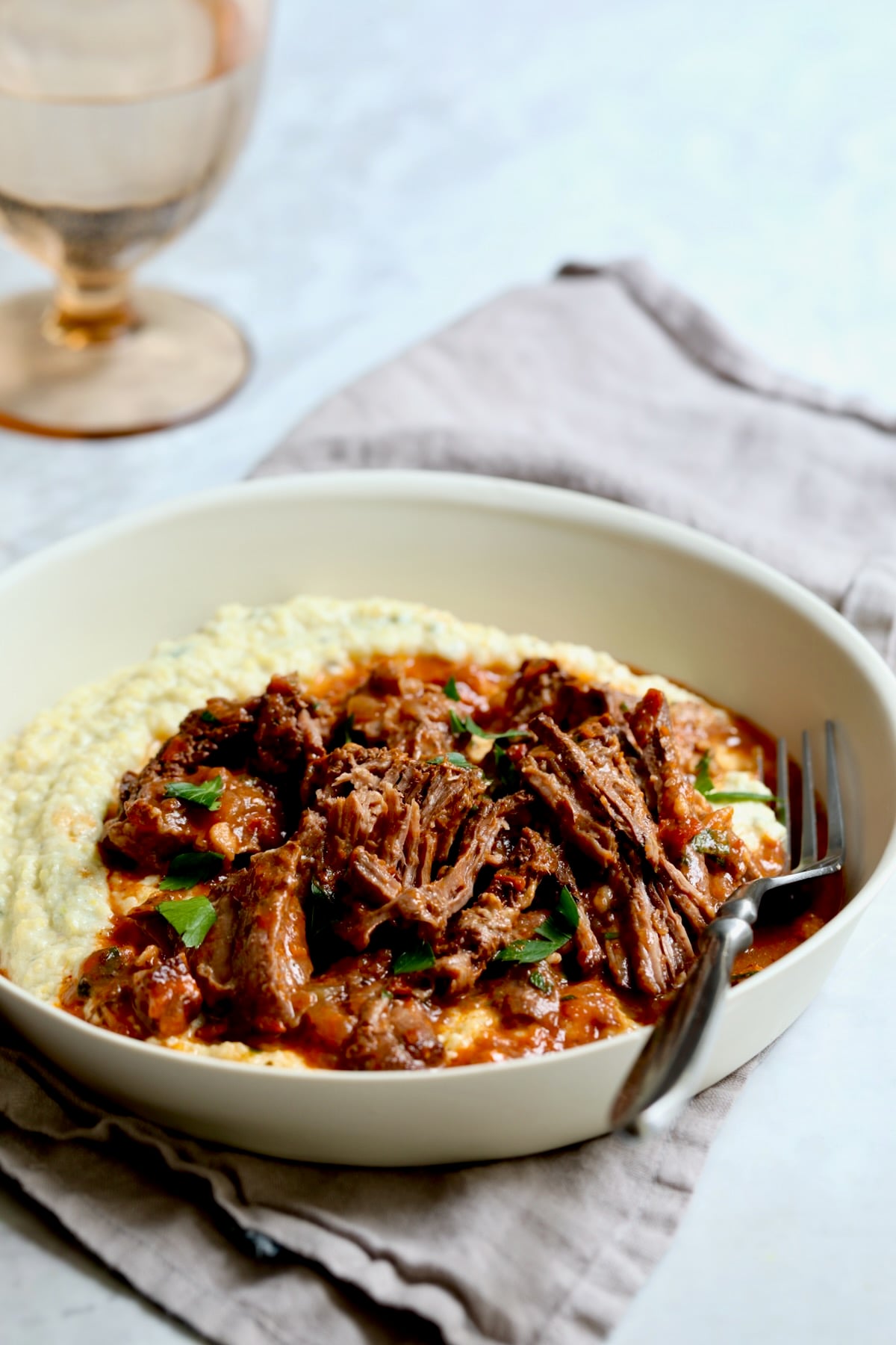 One serving of Italian Pot Roast (Stracotto) in white dinner bowl with fork.