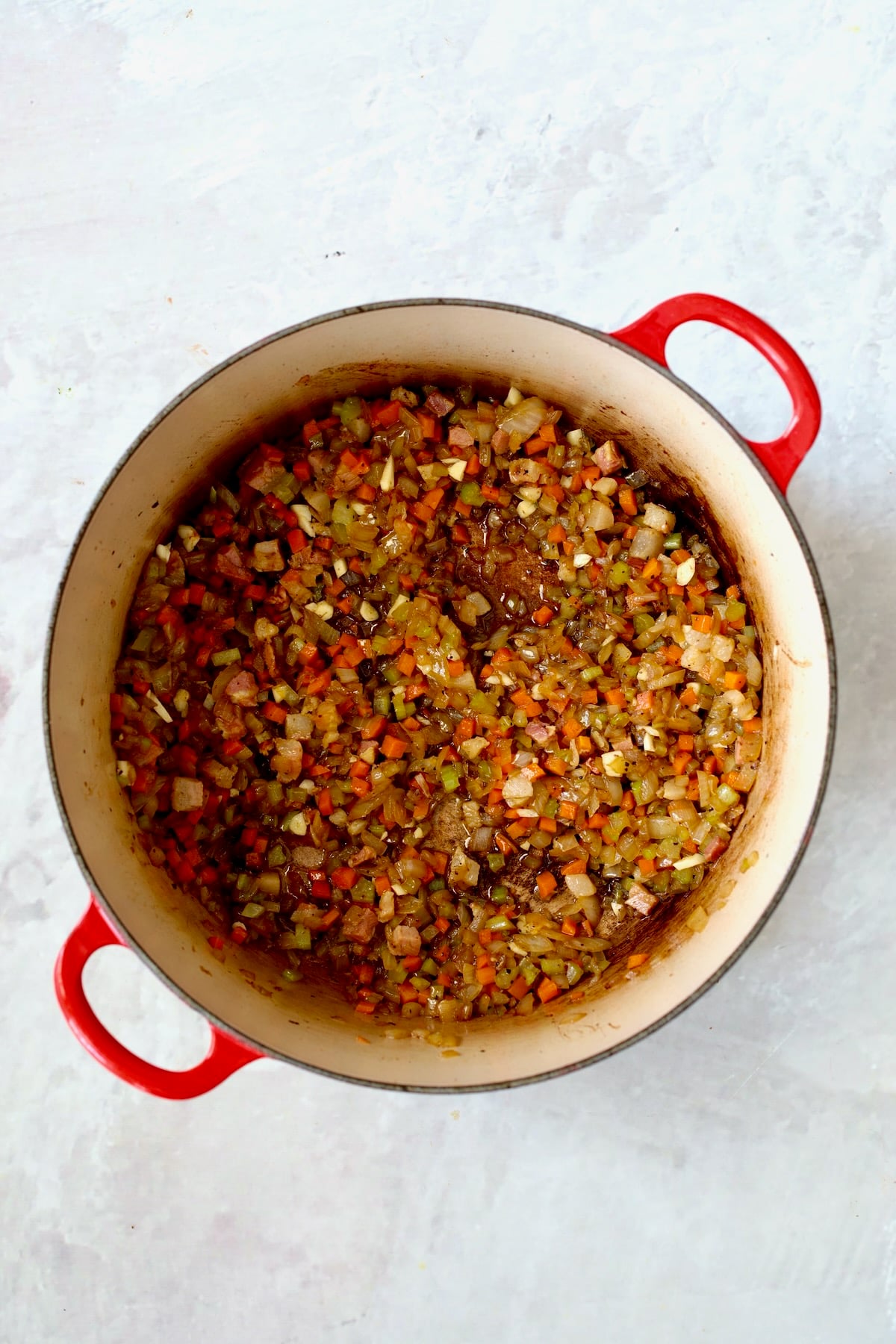 Cooked onions, carrots and celery in red enamel cast iron Dutch oven.
