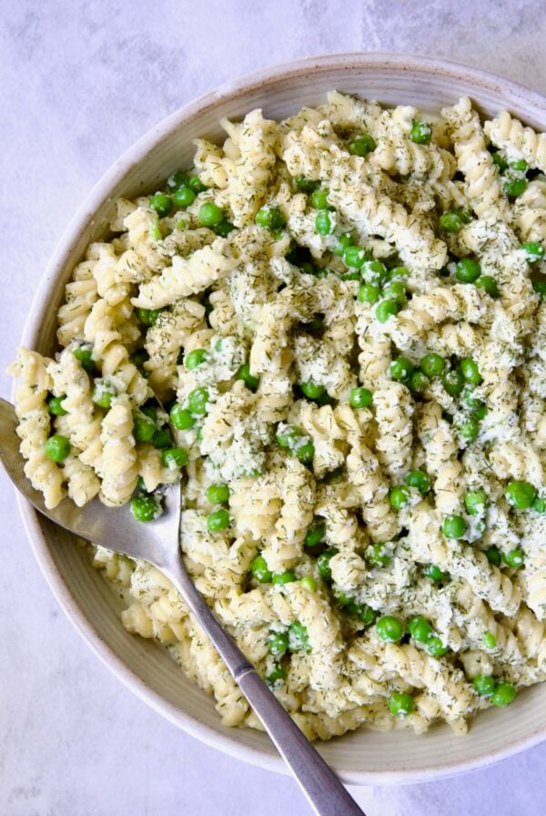 Creamy Cucumber Pasta Salad in white serving bowl with serving spoon.