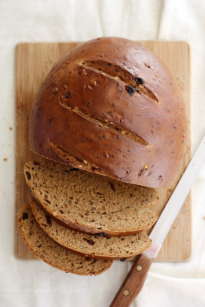 raisin walnut pumpernickel bread loaf on cutting board