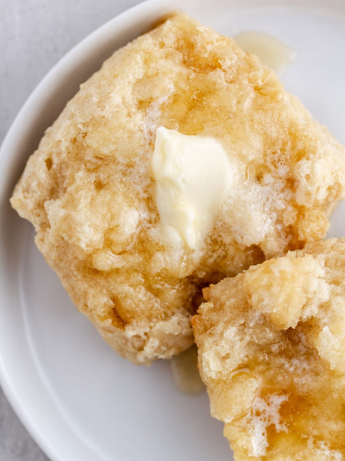 a split southern buttermilk biscuit on a plate with butter and honey on top.