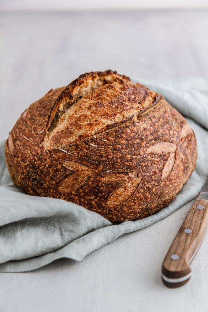 a loaf of sourdough bread on a napkin with a knife next to it