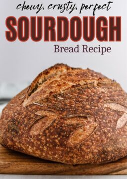 baked sourdough bread loaf on wooden board with scoring and text overlay.