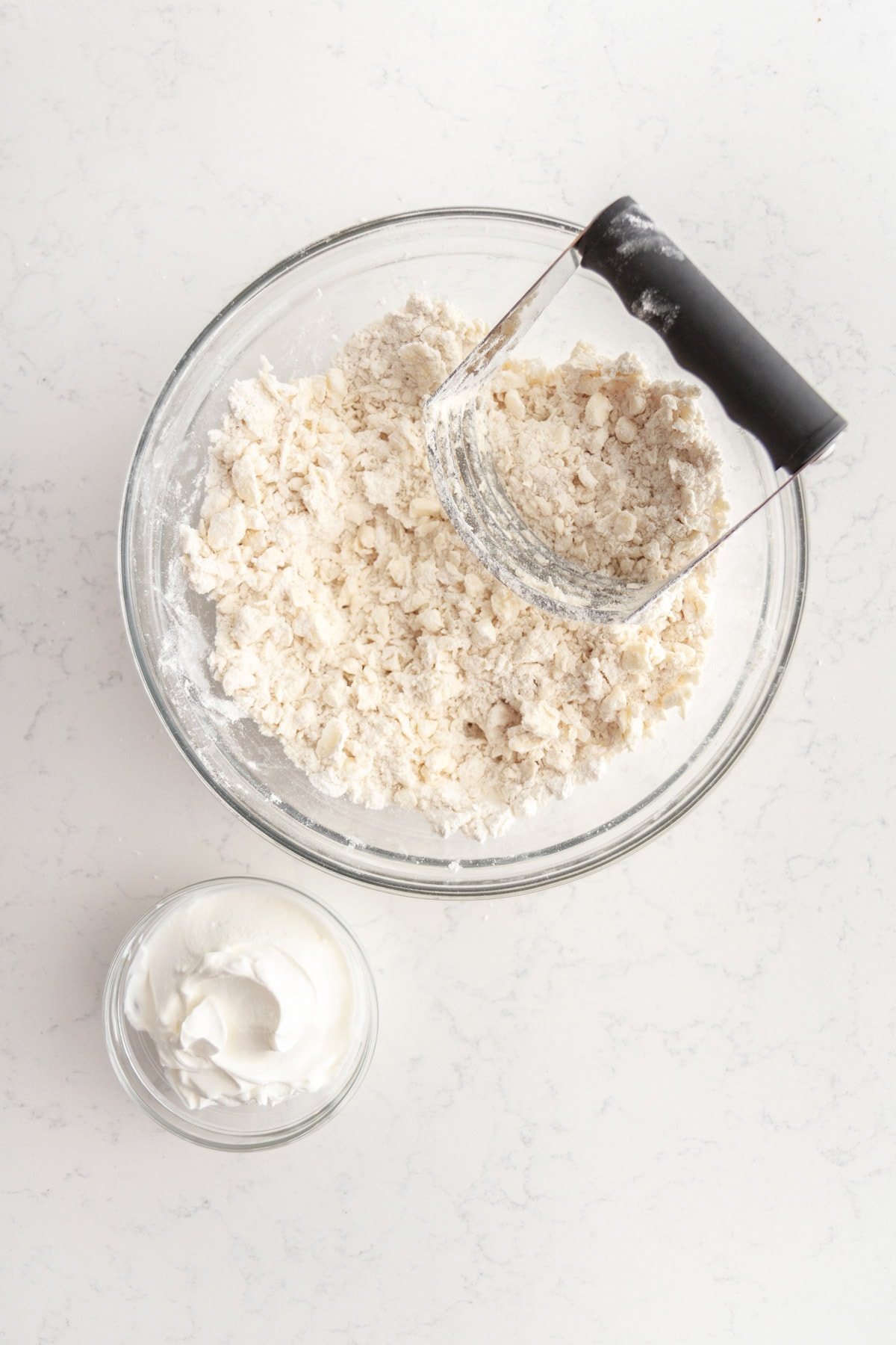butter and flour in a bowl with a bowl of sour cream off to the side.
