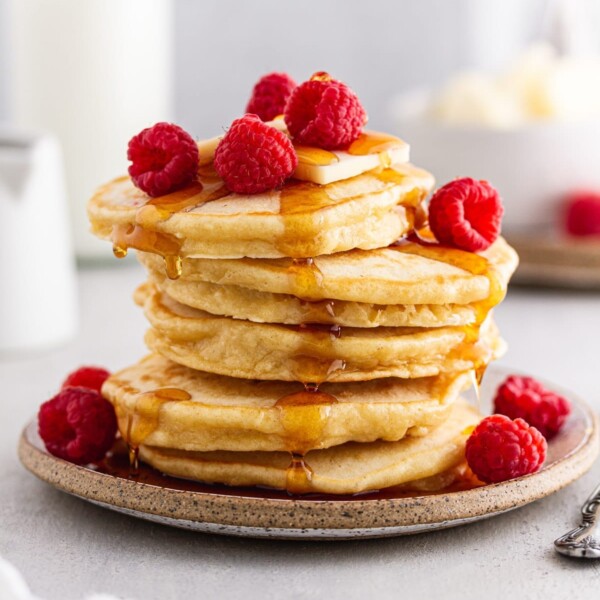 stack of sourdough pancakes with raspberries and maple syrup.