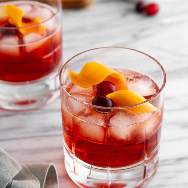 two holiday negronis in glasses on a surface.