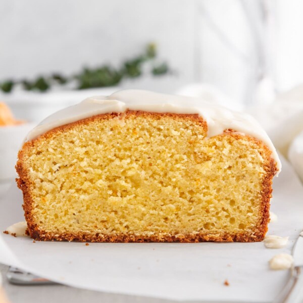 sliced iced clementine pound cake on parchment paper.