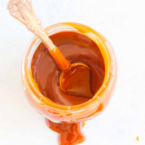 salted caramel sauce in jar with spoon sinking in.