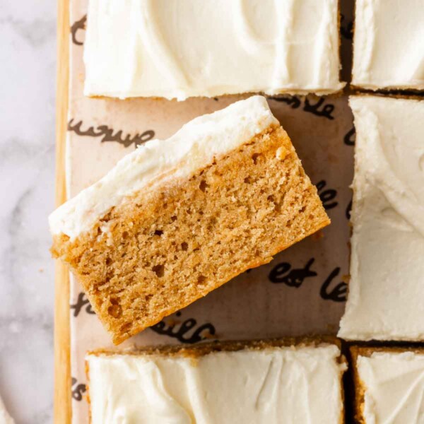 sliced banana bars with cream cheese frosting on parchment.