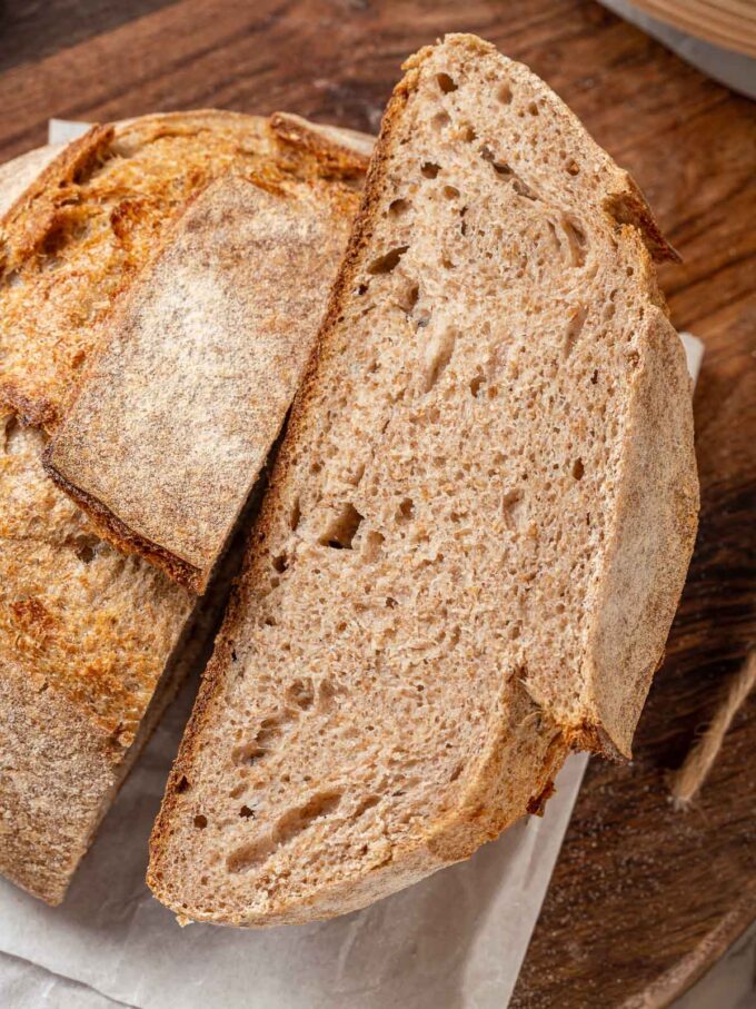 whole wheat sourdough loaf cut in half with interior texture showing.