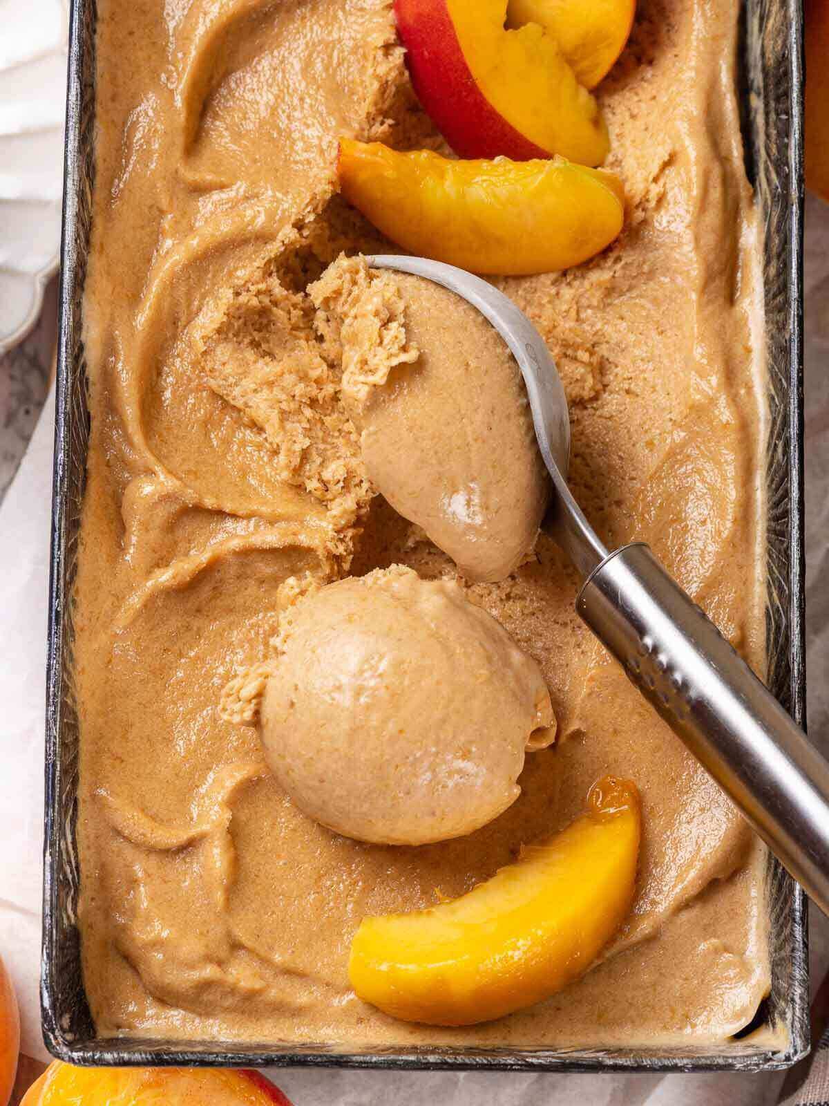 Peach ice cream in a metal pan.