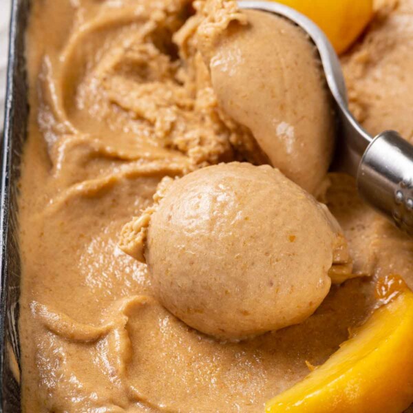 Peach ice cream being served with a vintage scoop.