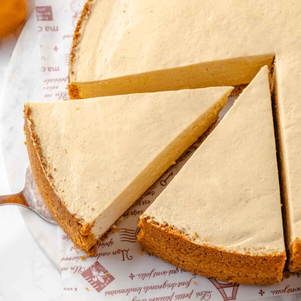 Slices of pumpkin no-bake cheesecake being pulled from the whole cheesecake.