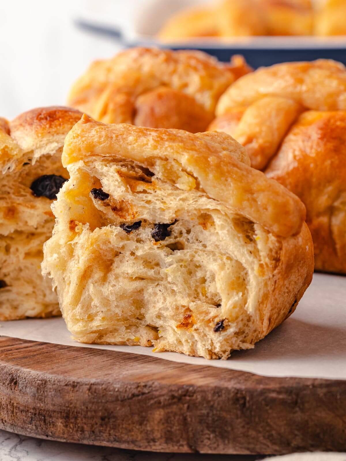 A hot cross bun torn in half, showing its soft, fluffy texture.