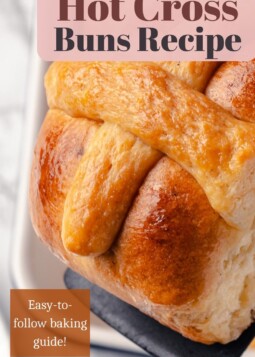 Close-up of a soft, fluffy hot cross bun topped with a vanilla dough cross.