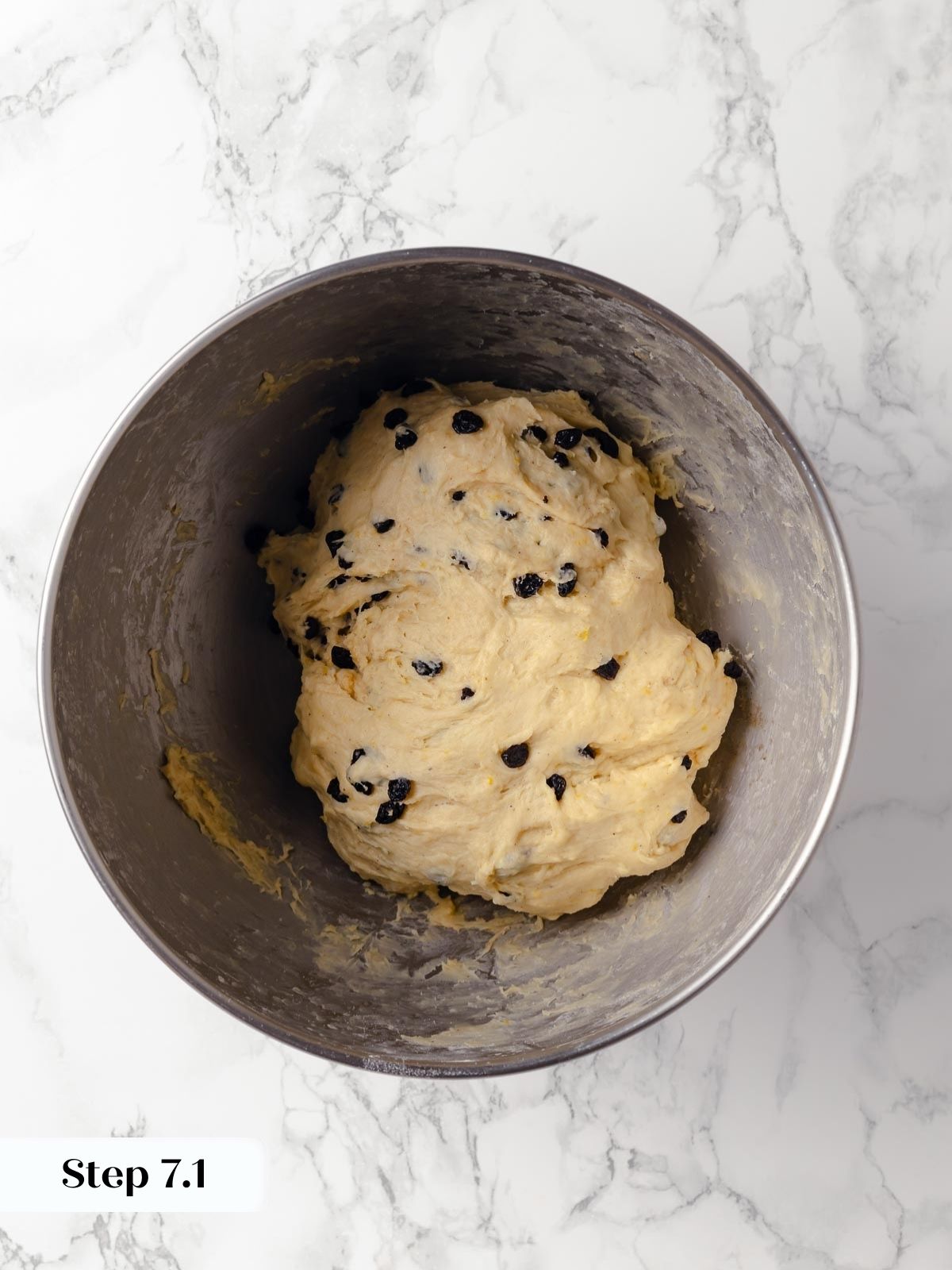 A bowl of dough speckled with plump, dark currants.