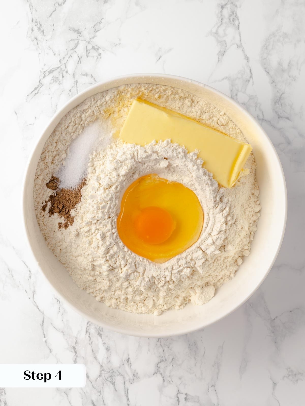 An egg added to a well in the flour mixture.