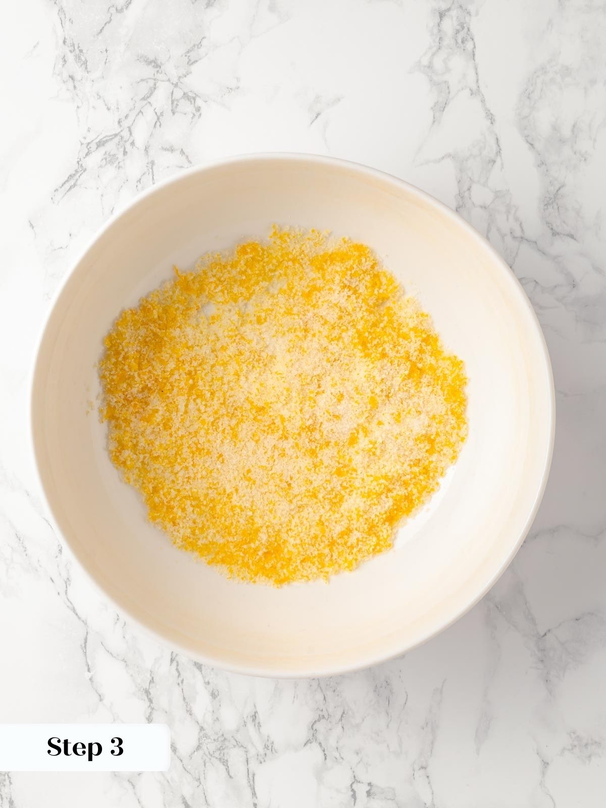 Fresh orange zest being mixed into granulated sugar.