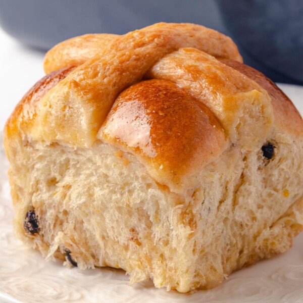 A single hot cross bun with a golden crust and soft inside.