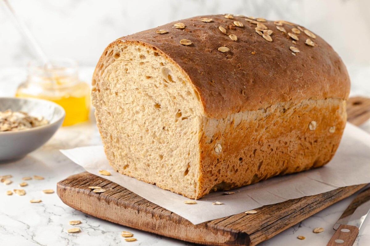 Whole loaf of homemade oatmeal bread on a cutting board.