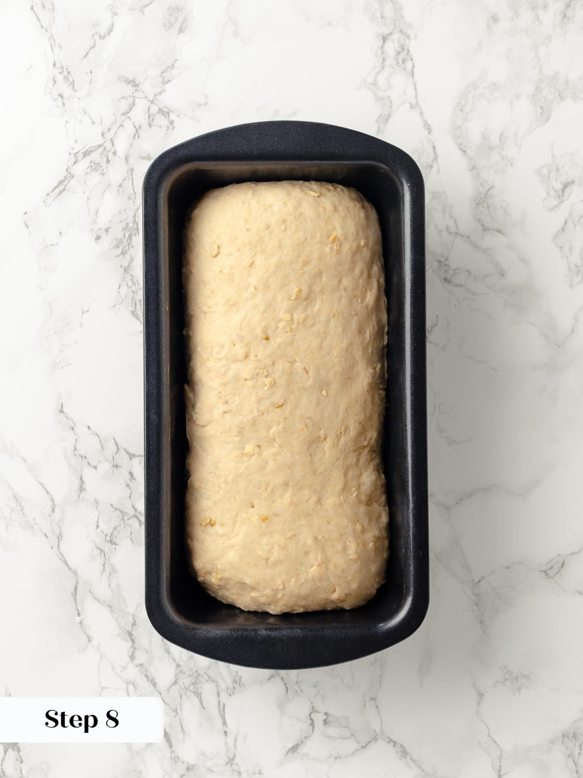Fresh oatmeal bread dough placed in a loaf pan.